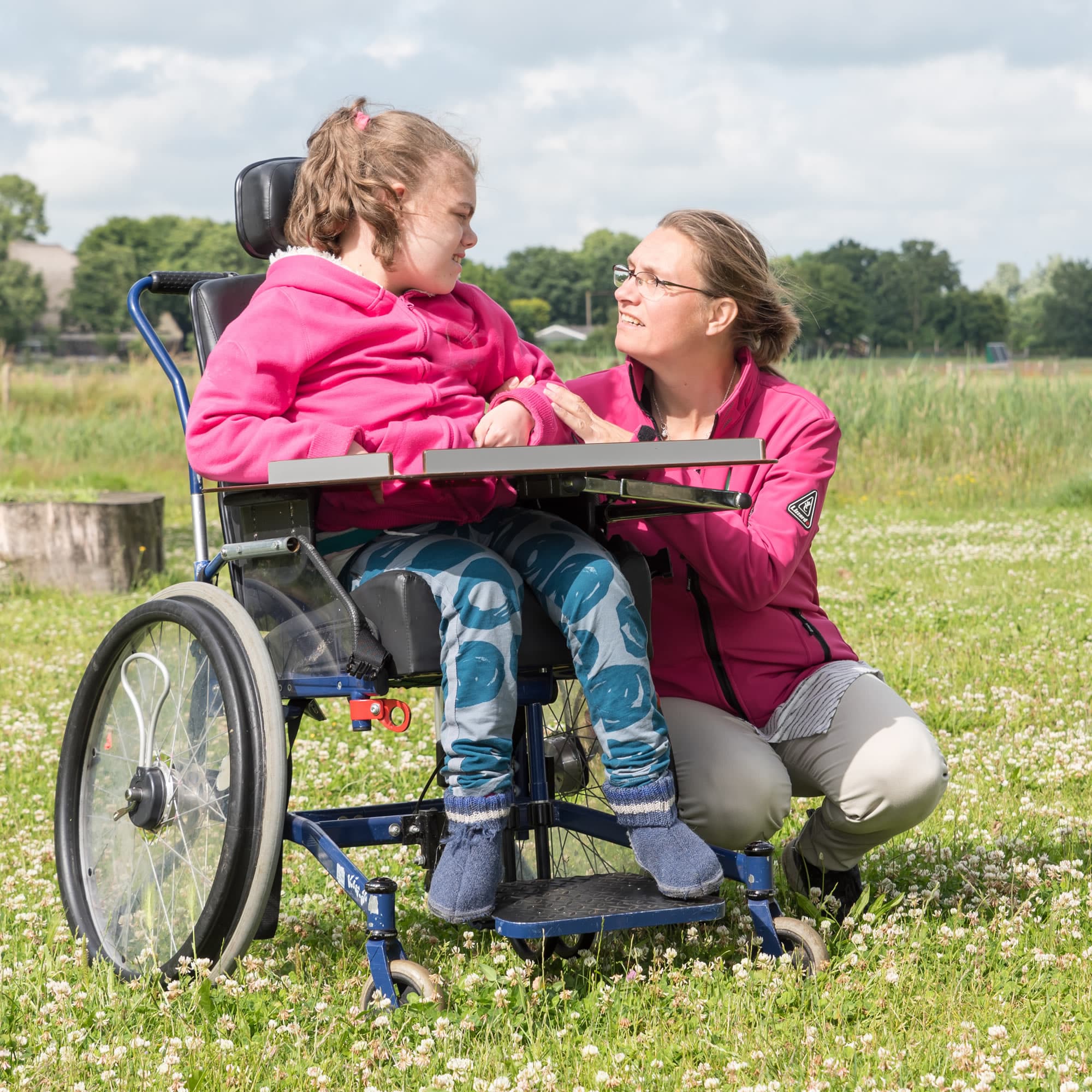 A support person talking with a wheelchair user outdoors