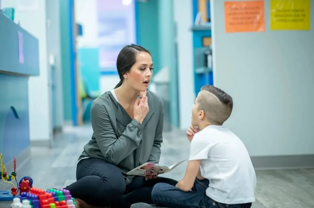 a young lady is providing therapy services to a child